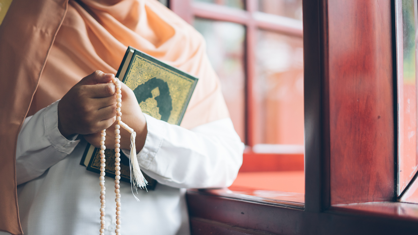 Woman in Hijab holding a Quran and Praying Beads Indoors